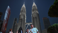 People walk past the Petronas Tower in Kuala Lumpur on October 18, 2026. (Photo by Jam STA ROSA / AFP)