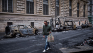 A man walks past a row of burnt out vehicles on Rue Yves Toudic destroyed after a nationwide protest against the 