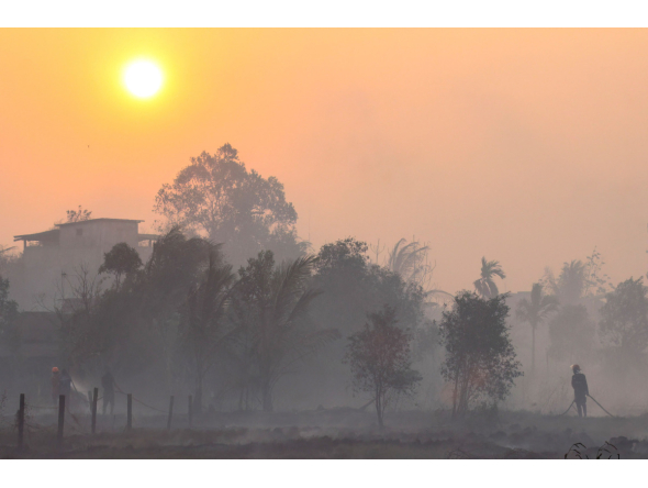 Firefighters and residents use hoses to extinguish spreading wildfires amid dense smoke and a hazy sunset in Banjarbaru, South Kalimantan province, on October 21, 2026. (Photo by MUDA SAGALA / AFP)
