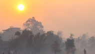 Firefighters and residents use hoses to extinguish spreading wildfires amid dense smoke and a hazy sunset in Banjarbaru, South Kalimantan province, on October 21, 2026. (Photo by MUDA SAGALA / AFP)