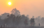 Firefighters and residents use hoses to extinguish spreading wildfires amid dense smoke and a hazy sunset in Banjarbaru, South Kalimantan province, on October 21, 2026. (Photo by MUDA SAGALA / AFP)