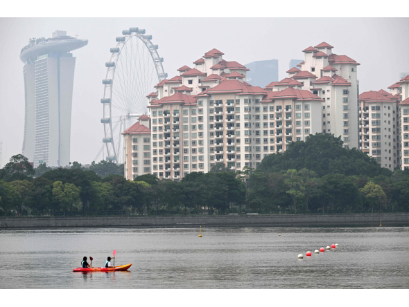 People row a canoe along the Kallang river as the haze eases in Singapore on October 23, 2026. (Photo by Roslan RAHMAN / AFP)