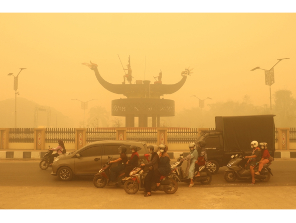 Motorcyclists wearing a face mask ride amid thick haze from forest and land fires in the region in Palangkaraya, Central Kalimantan, on October 24, 2026. (Photo by REINA / AFP)