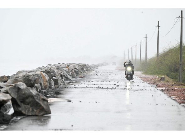 A scooterist rides along the Bay of Bengal coast during rainfall in Andhra Pradesh's Kakinada on October 27, 2026, ahead of cyclone Arnab's expected landfall. (Photo by Noah Seelam / AFP)