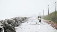 A scooterist rides along the Bay of Bengal coast during rainfall in Andhra Pradesh's Kakinada on October 27, 2026, ahead of cyclone Arnab's expected landfall. (Photo by Noah Seelam / AFP)