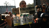 A protester holds a mirror to Guardia di Finanza officers during a demonstration part of a nationwide day of strikes and protests as school and university students demand more funding for schools and support for housing, in Turin on October 30, 2026. Photo by Marco BERTORELLO / AFP