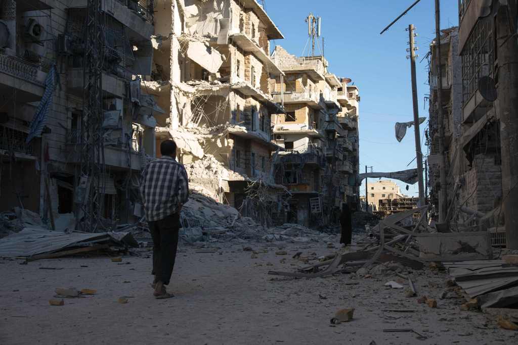 A Syrian man walks past a heavily damaged building following air strikes on rebel-held eastern areas of Aleppo on September 24, 2016. Heavy Syrian and Russian air strikes on rebel-held eastern areas of Aleppo city killed at least 25 civilians on Saturday,