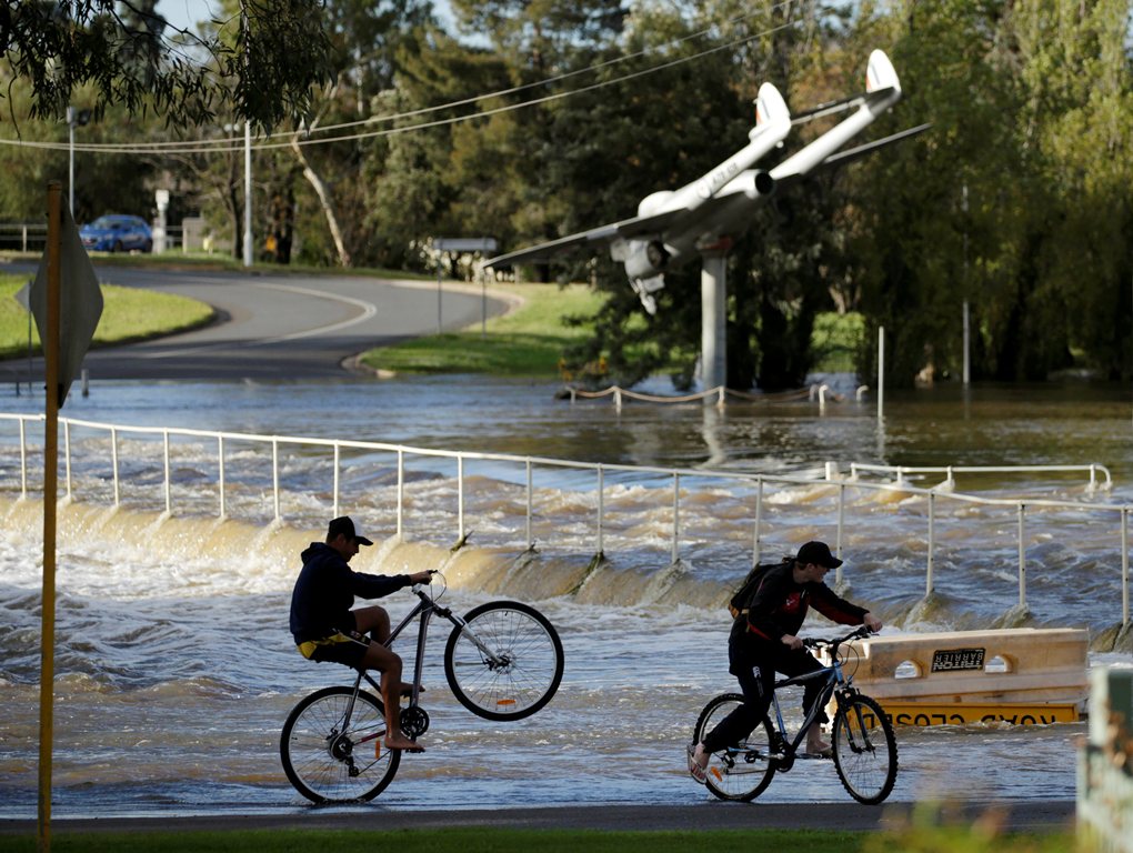 Boys bicycle out of floodwaters after heavy rains inundated the midwestern New South Wales town of Forbes, Australia, September 27, 2016. REUTERS/Jason Reed