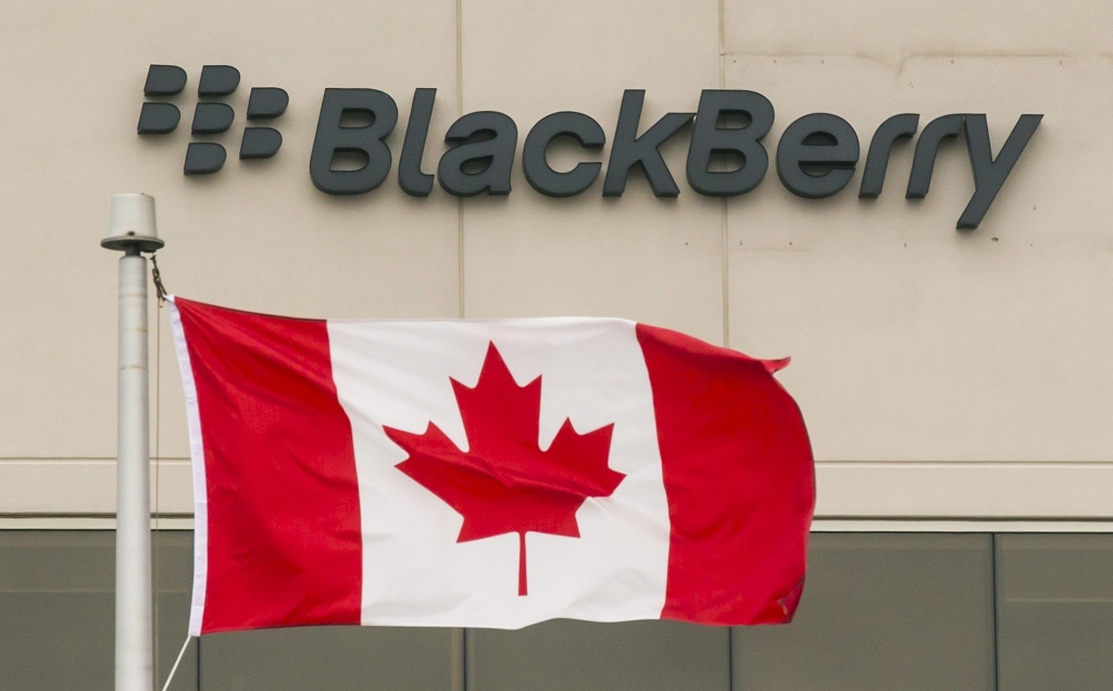A Blackberry logo hangs behind a Canadian flag at their offices on the day of their annual general meeting for shareholders in Waterloo, Canada June 23, 2015. REUTERS/Mark Blinch/File Photo
