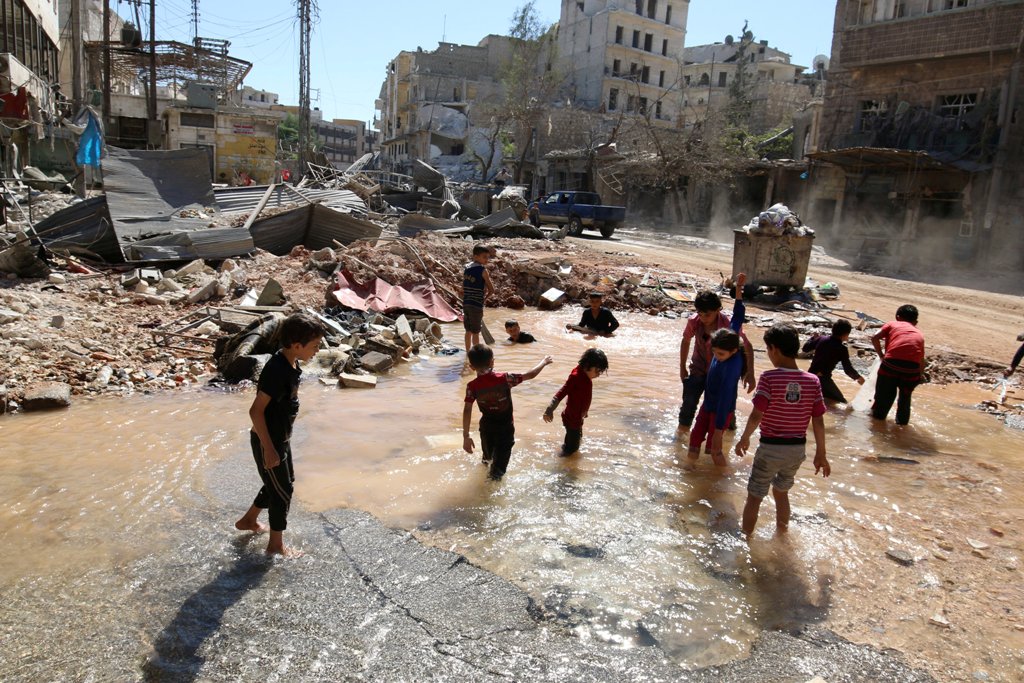 Children play with water from a burst water pipe at a site hit yesterday by an air strike in Aleppo's rebel-controlled al-Mashad neighbourhood, Syria, September 30, 2016. REUTERS/Abdalrhman Ismail