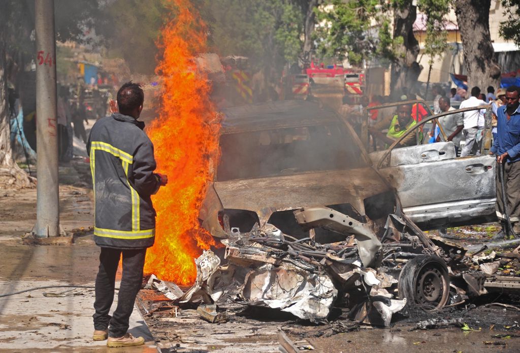 Firefighters douse the flaming wreckage of car after a suicide car bomb attack in Mogadishu on October, 1, 2016. AFP / Mohamed ABDIWAHAB