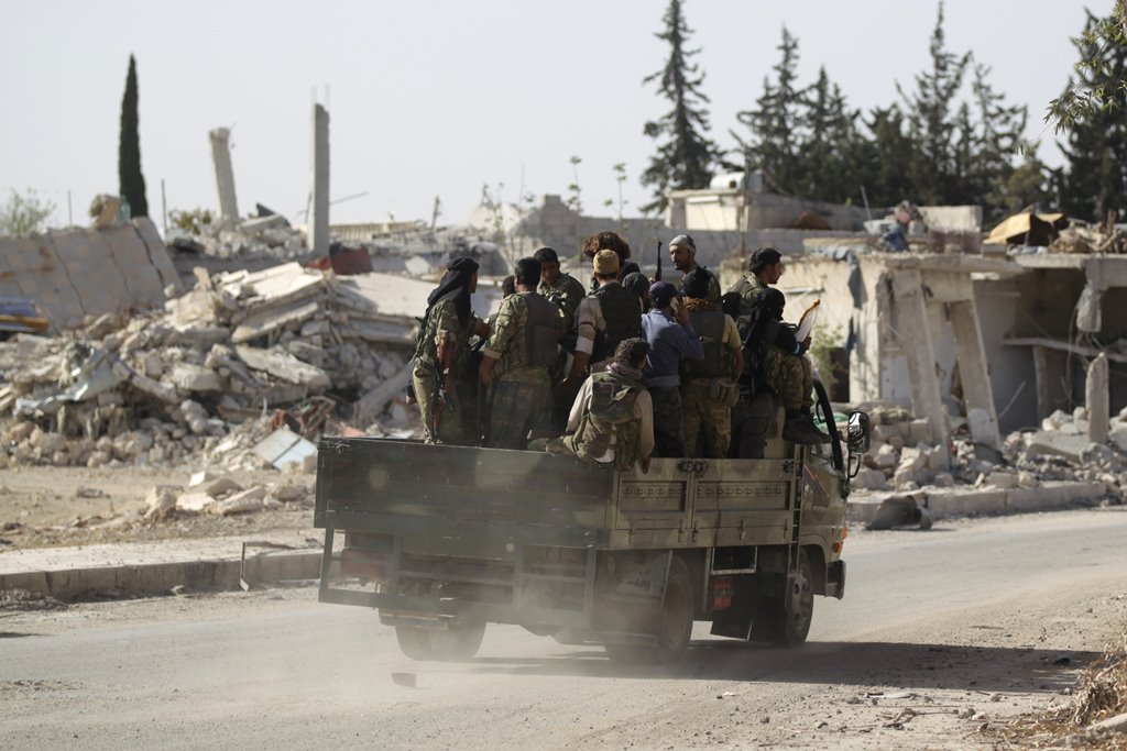 Rebel fighters drive past damaged buildings in al-Rai town, northern Aleppo countryside, Syria October 2, 2016. REUTERS/Khalil Ashawi