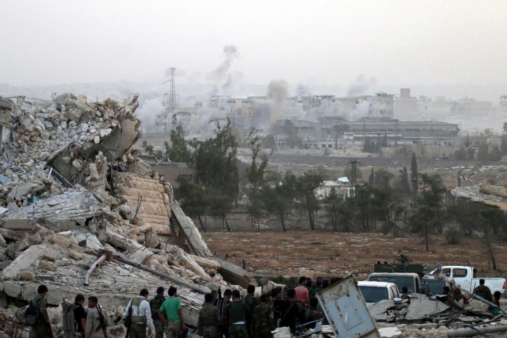 Syrian regime forces gather at the Kindi Hospital as smoke billows following aistrikes on Aleppo on October 2, 2016. AFP / GEORGE OURFALIAN