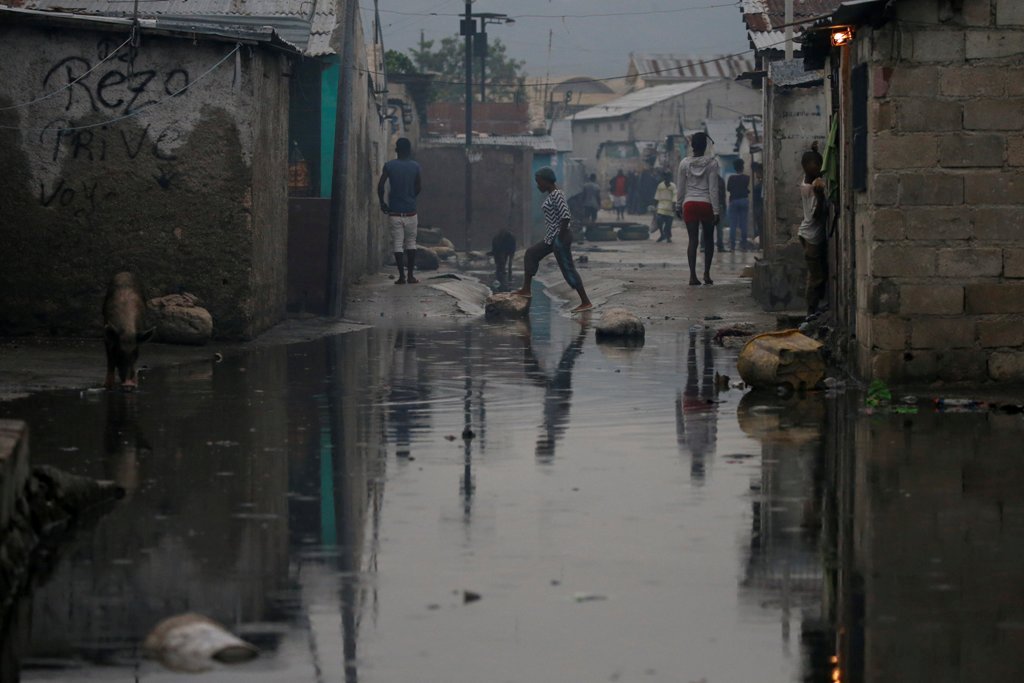 People walk on a flooded street after Hurricane Matthew passes Cite-Soleil in Port-au-Prince, Haiti, October 5, 2016. REUTERS/Carlos Garcia Rawlins

