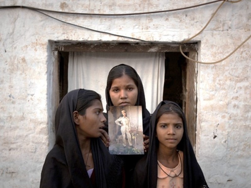 File photo of the daughters of Aasia Bibi with an image of their mother, standing outside their residence. Reuters