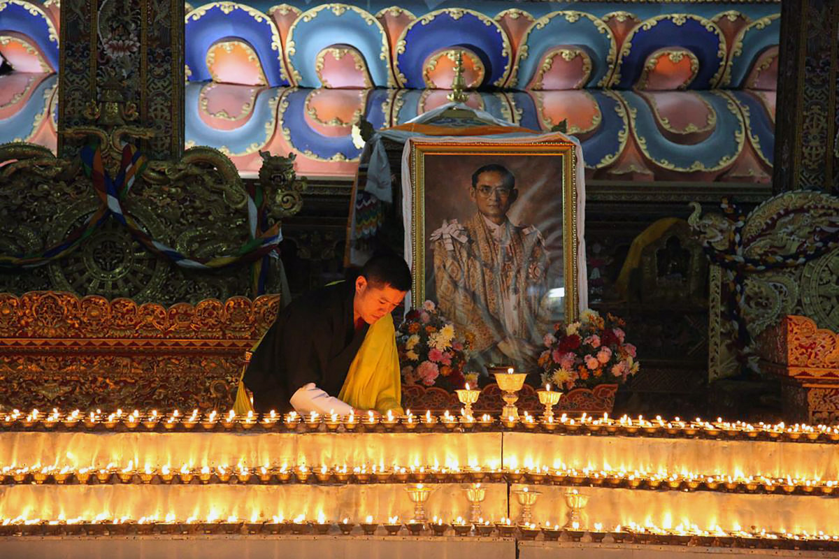 This photograph released on October 13, 2016 by Bhutan's Royal Office for Media on Bhutanese King Jigme Khesar's Facebook page shows King Jigme Khesar at the Kuenra of the Tashichhodzong in Thimpu lighting candles next to a portrait of Thailand's King Bhu