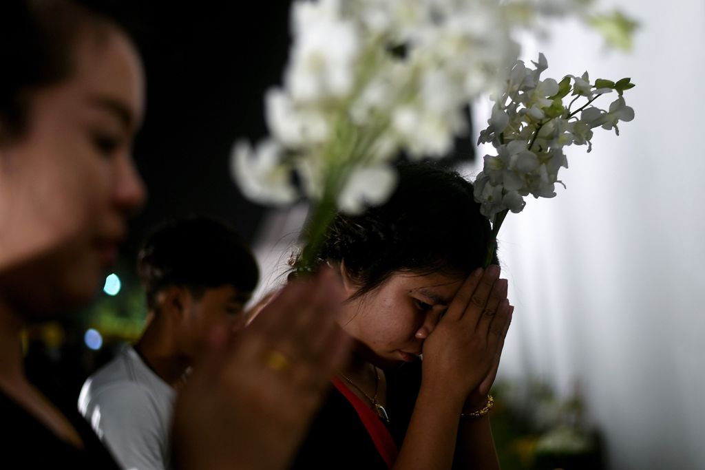 Thai mourners hold flowers as they offer prayers outside the Grand Palace, where the late King Bhumibol Adulyadej is lying in state in Bangkok on October 16, 2016. / AFP / MANAN VATSYAYANA