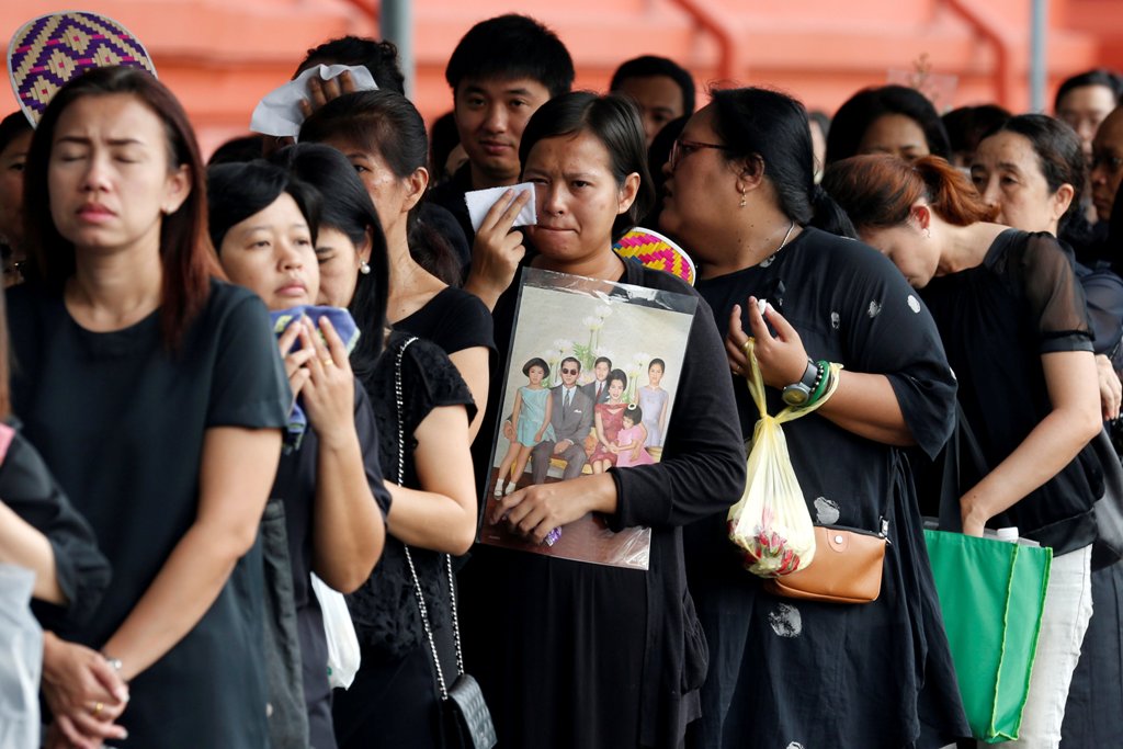 A mourner holds up a picture of Thailand's late King Bhumibol Adulyadej as she waits in line to pay respects to him outside the Grand Palace in Bangkok, Thailand, October 19, 2016. REUTERS/Chaiwat Subprasom