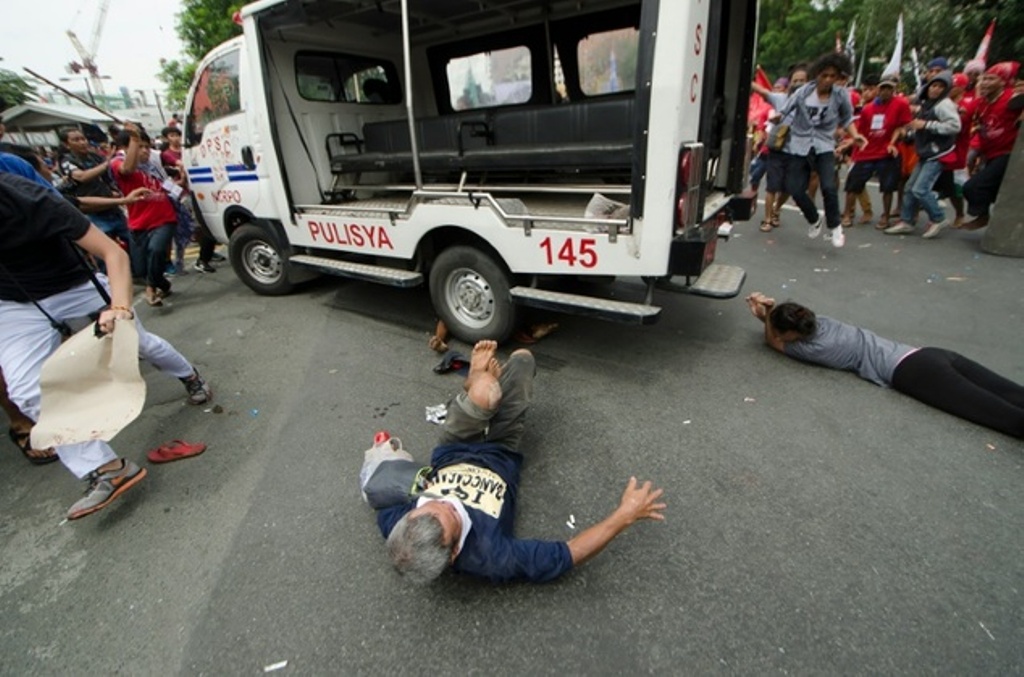 Protesters lie on the ground after being hit by a police van during a rally in front of the US embassy in Manila on October 19, 2016 ©Rob Reyes (AFP)