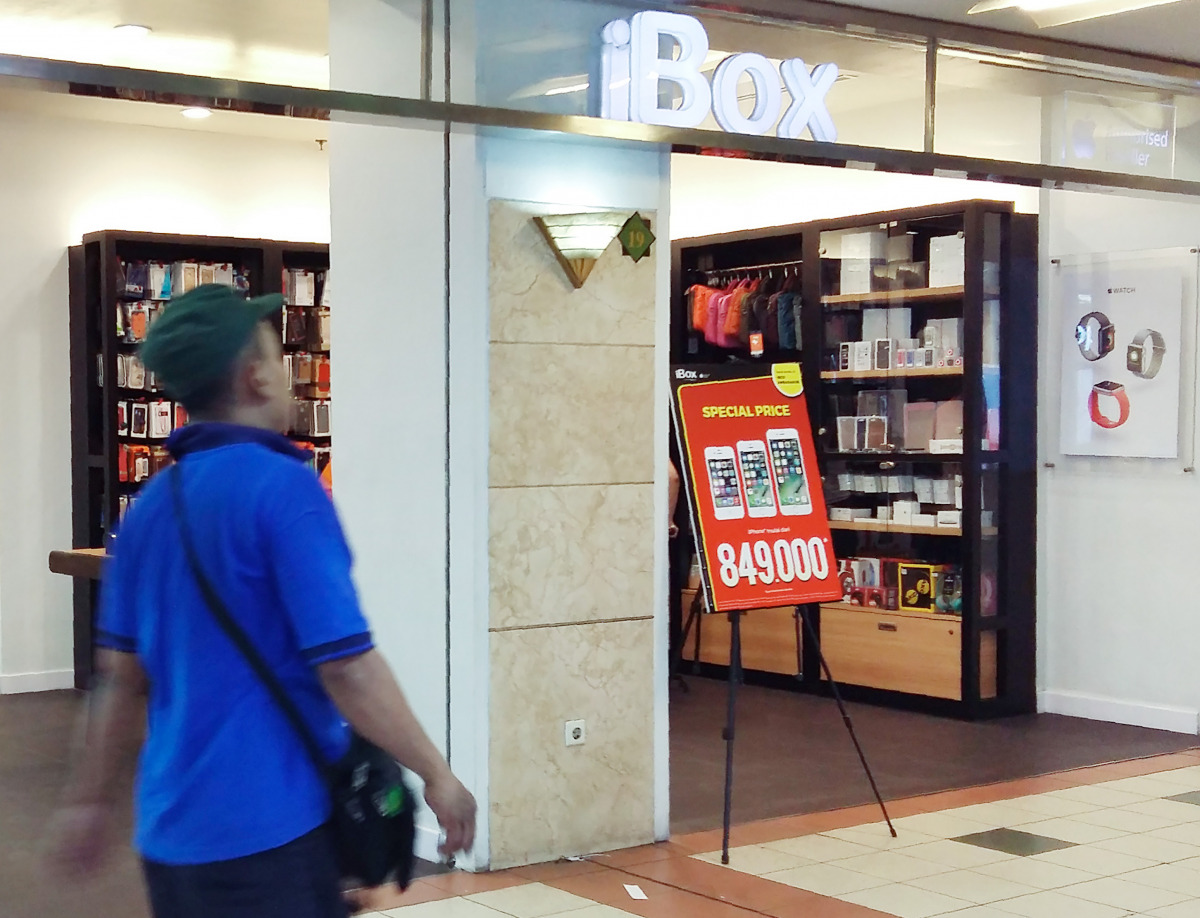 This picture taken on October 22, 2016 shows a man walking past an authorized Apple store in a shopping mall in Jakarta. Apple is battling to gain a foothold in Indonesia after nationalistic regulations hit the US tech giant's efforts to compete in the bo