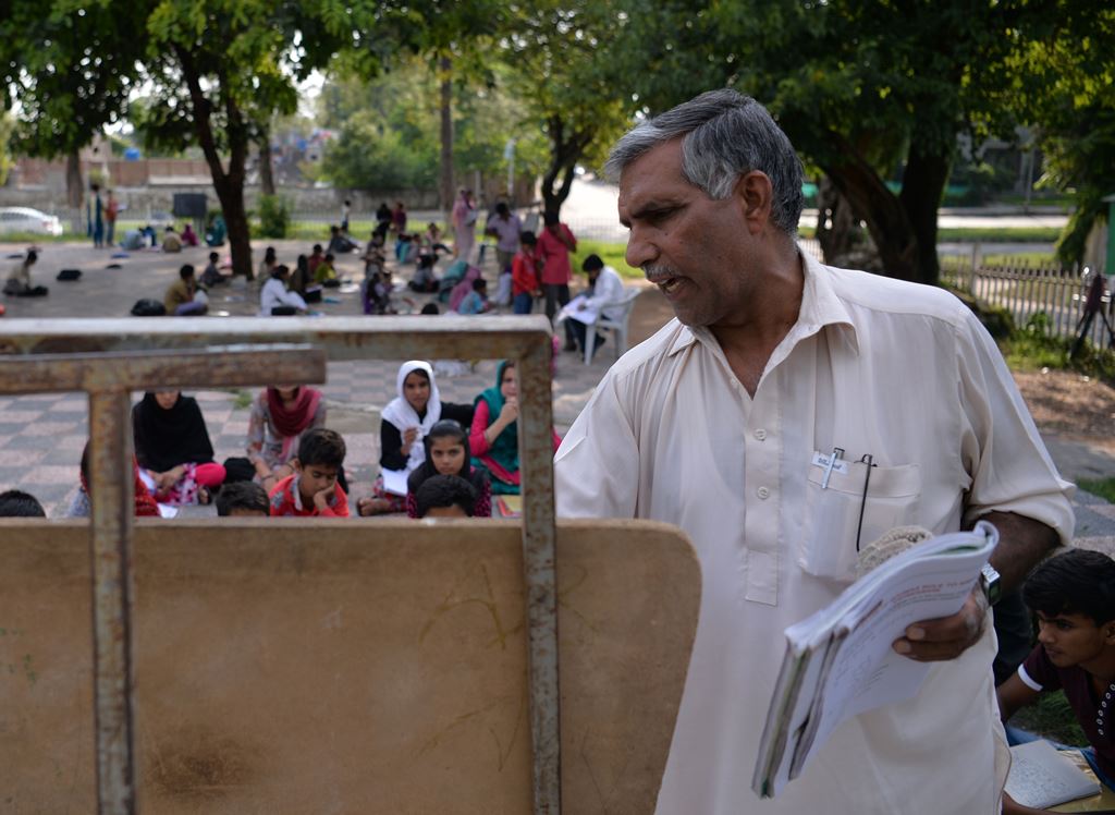 Muhammad Ayub, an employee with Pakistan's Civil Defence service, teaches pupils at a makeshift school in a park in Islamabad. AFP / AAMIR QURESHI /