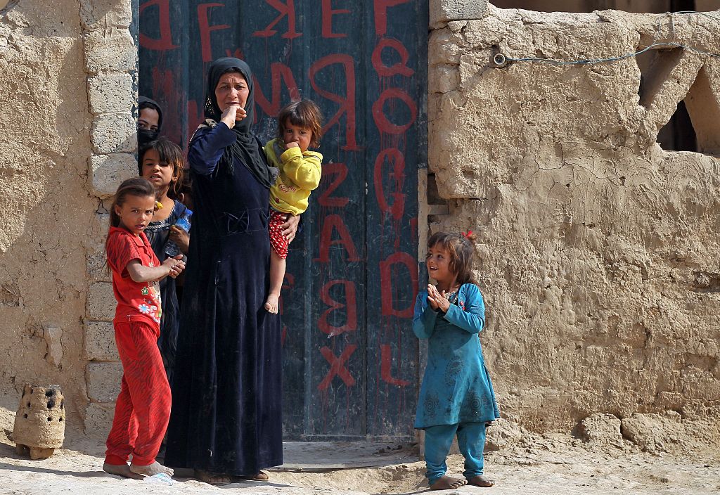 A woman look at Iraqi forces in the village of al-Khuwayn, south of Mosul, after recapturing it from Islamic State (IS) group jihadists on October 23, 2016, in part of an ongoing operation to tighten the noose around Mosul and reclaim the last major Iraqi