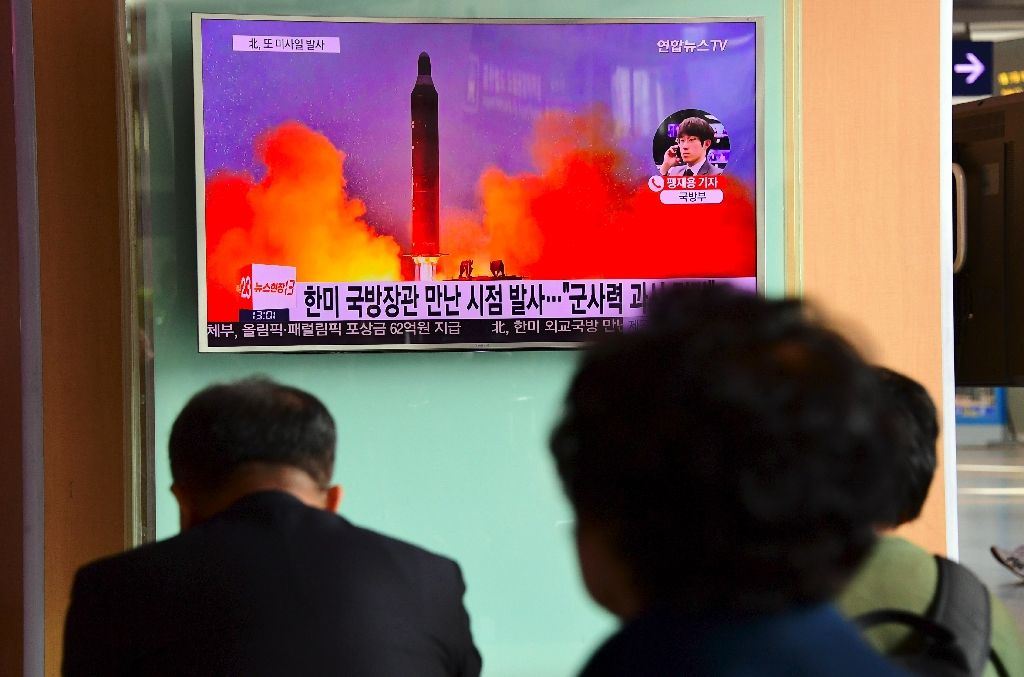 People watch a television news report showing file footage of North Korea's missile launch at a railway station in Seoul on October 20, 2016 (AFP Photo/Jung Yeon-Je)