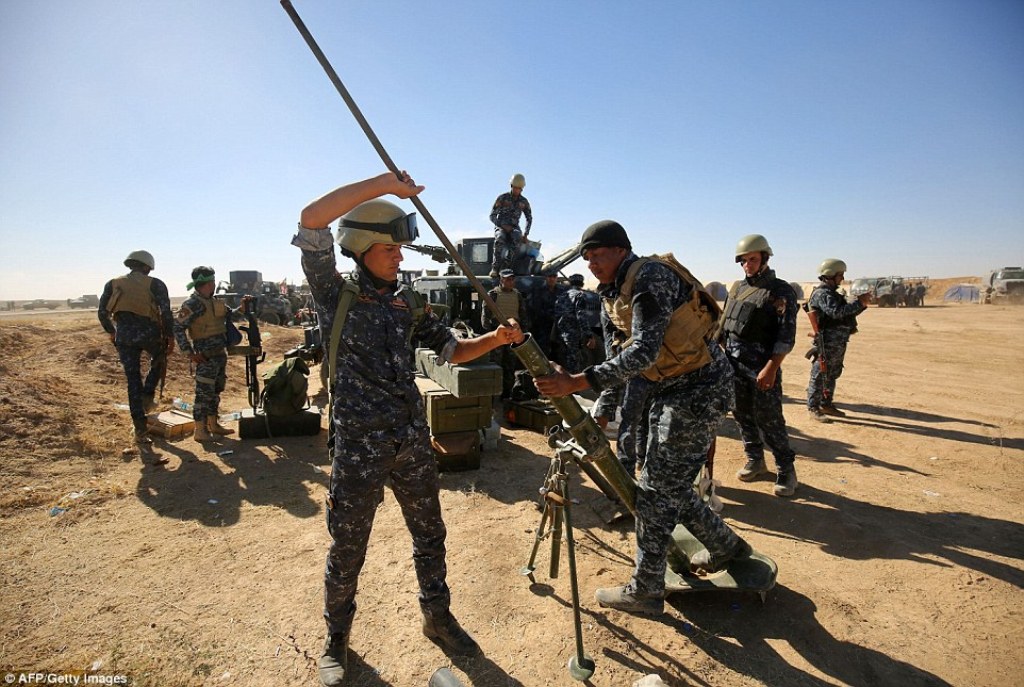 Iraqi policemen clean a weapon yesterday as 30,000 pro-government troops prepare to launch an attack on Mosul in Iraq. Iraq assembles its troops ahead of Mosul offensive against ISIS. / AFP.