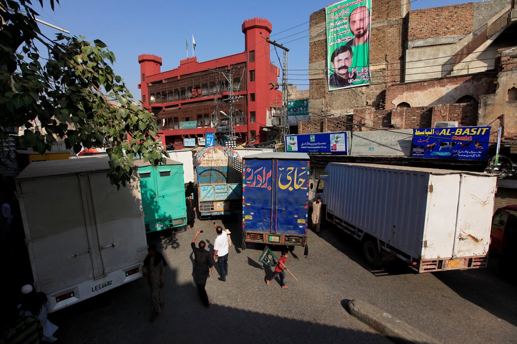 A boy holding a flag walks past trucks, used to block a venue of a planned protest gathering organised by Awami Muslim League, a political ally party of Imran Khan's Pakistan Tehreek-e-Insaf (PTI), in Rawalpindi, Pakistan. Reuters/Faisal Mahmood