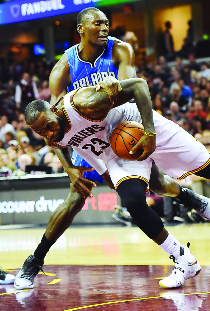 Orlando Magic centre Bismack Biyombo (11) grabs Cleveland Cavaliers forward LeBron James (23) during the second half at Quicken Loans Arena on Saturday. The Cavaliers won 105-99.