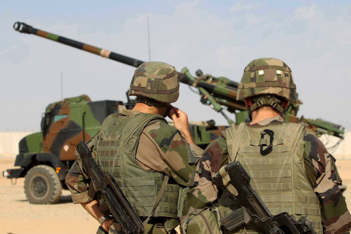 French soldiers stand next to a CAESAR, a French self-propelled 155 mm/52-calibre gun-howitzer, in the Qayyarah base south of Mosul on October 31, 2016 as they provide military support for Iraq forces fighting to retake the city of Mosul from the hands of