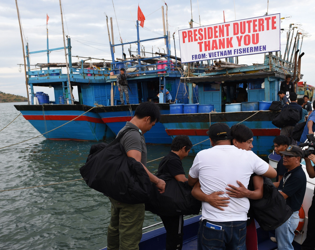 A Vietnamese fisherman (2nd R, facing camera) hugs a Filipino government employee (C, in white shirt) during a send-off ceremony at the wharf in Sual town, Pangasinan province, north of Manila on November 2, 2016, while other Vietnamese fishermen prepare 