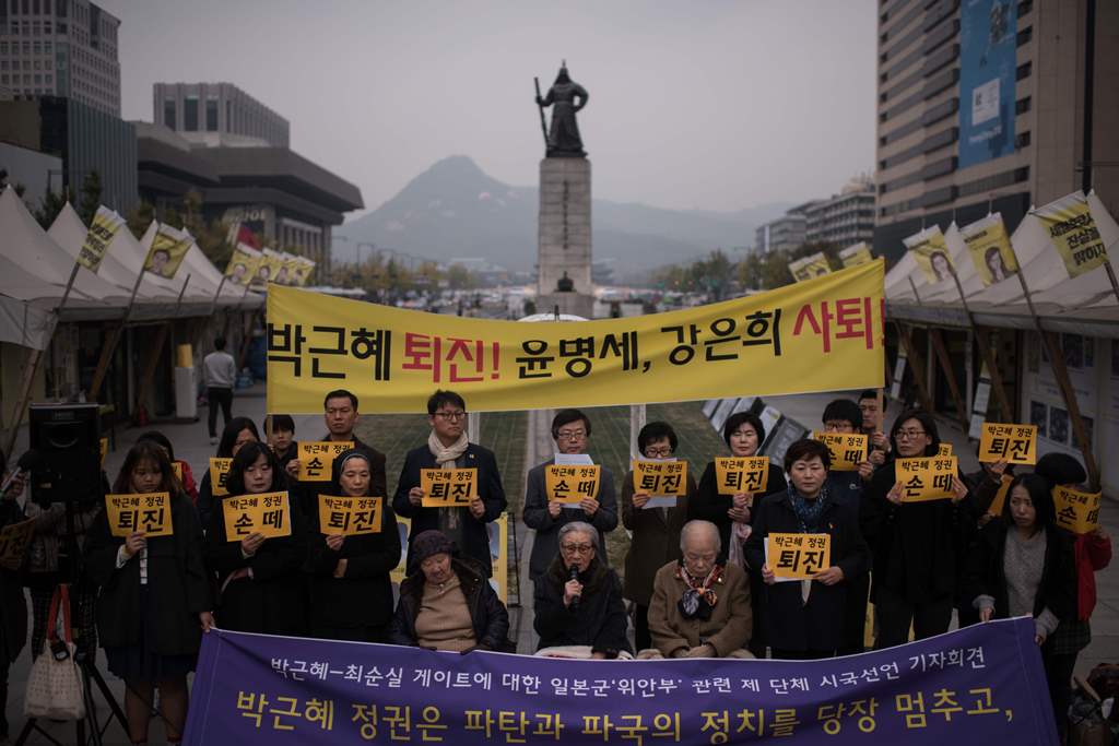 Protesters hold placards reading 