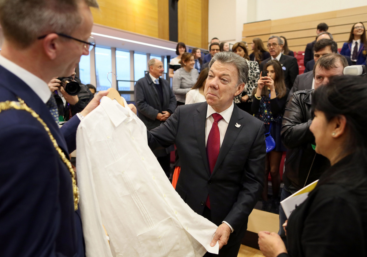 Colombian President Juan Manuel Santos (C) is presented with an Irish Linen shirt by Belfast Lord Mayor Alderman Brian Kingston (L) and made by Maria Cardens (R) during a visit to the Girwood community Hub in north Belfast on November 3, 2016. Santos is t