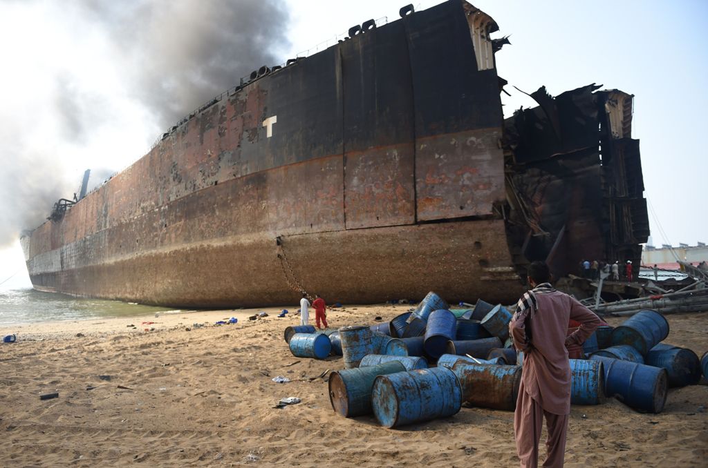 A Pakistani man looks at the wreckage of a burning ship a day after a gas cylinder explosion at the Gadani shipbreaking yard, some 50 kilometres (30 miles) west of Karachi, on November 2, 2016.  AFP / RIZWAN TABASSUM