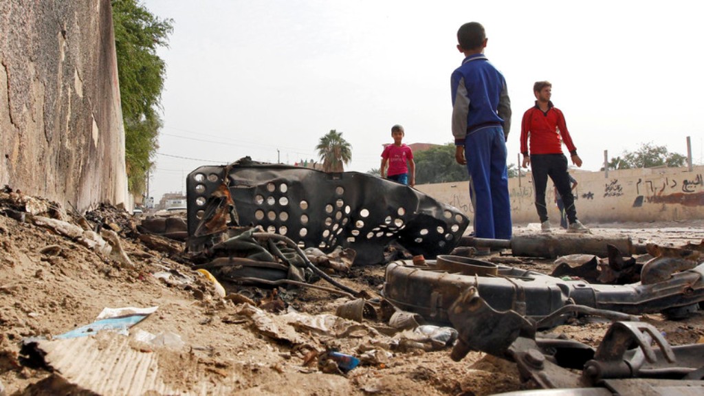 Iraqi youth gather by wreckage at the site of a car bomb that exploded the previous night in Baghdad's Hurriyah neighbourhood on October 31, 2016. (AFP)