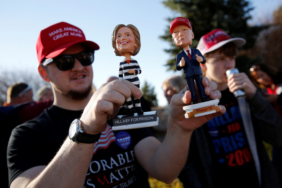 A man holds bobble-head dolls of Clinton and Trump as supporters stand in line to attend a rally with Republican presidential nominee Donald Trump in a cargo hangar at Minneapolis Saint Paul International Airport in Minneapolis, Minnesota, U.S. November 6