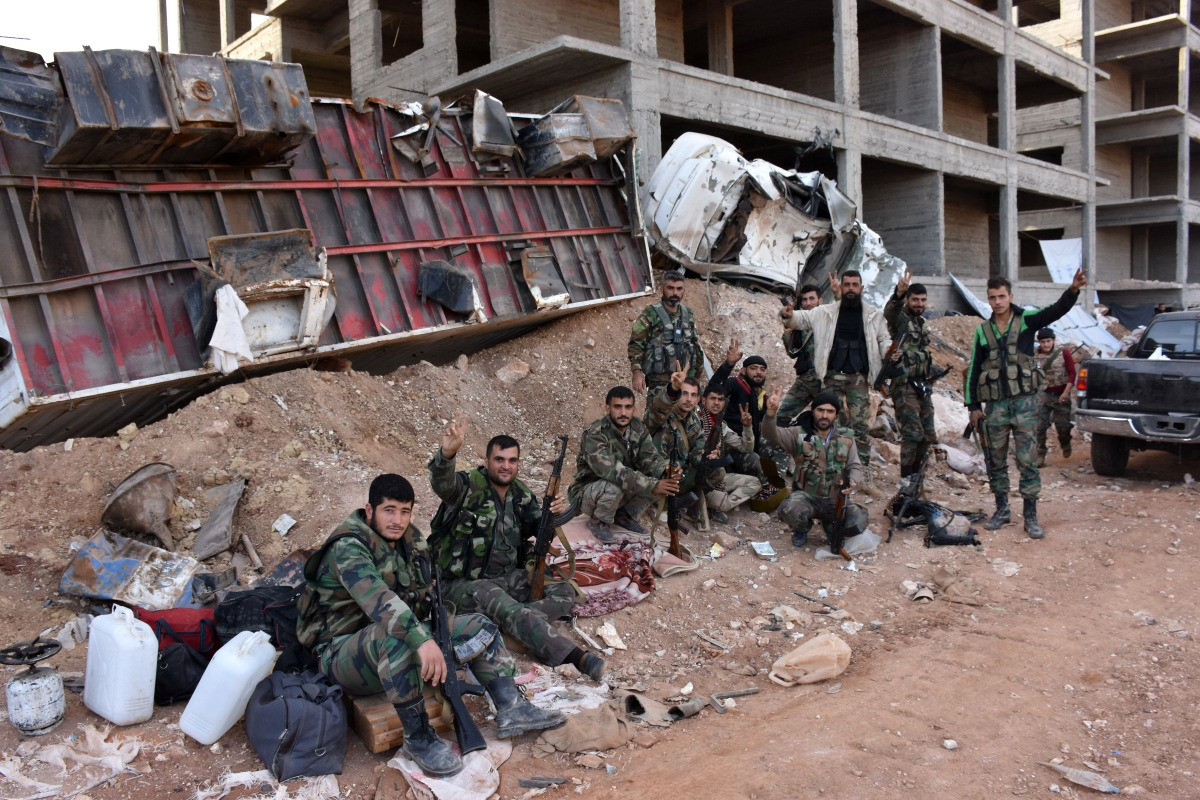 Syrian pro-government forces flash the V-sign as they hold a position in Aleppo's 1070 district on November 8, 2016, after seizing it from rebel fighters. Syrian state media said government forces had advanced southwest of divided second city Aleppo, seiz
