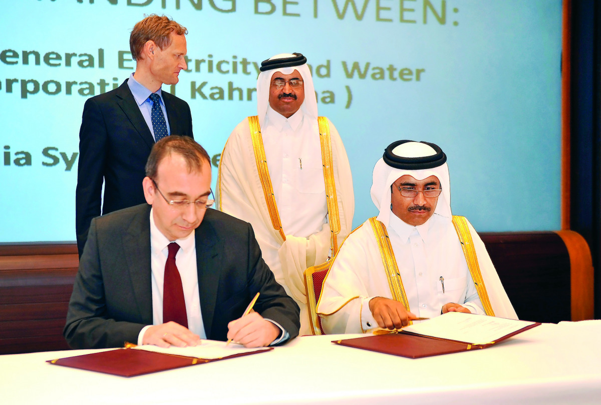 Essa bin Hilal Al-Kuwari (right) and Markus Berger signing  the document in the presence of Minister of Energy and Industry, H E Dr Mohammed bin Saleh Al Sada yesterday. Pic: Abdul Basit / The Peninsula