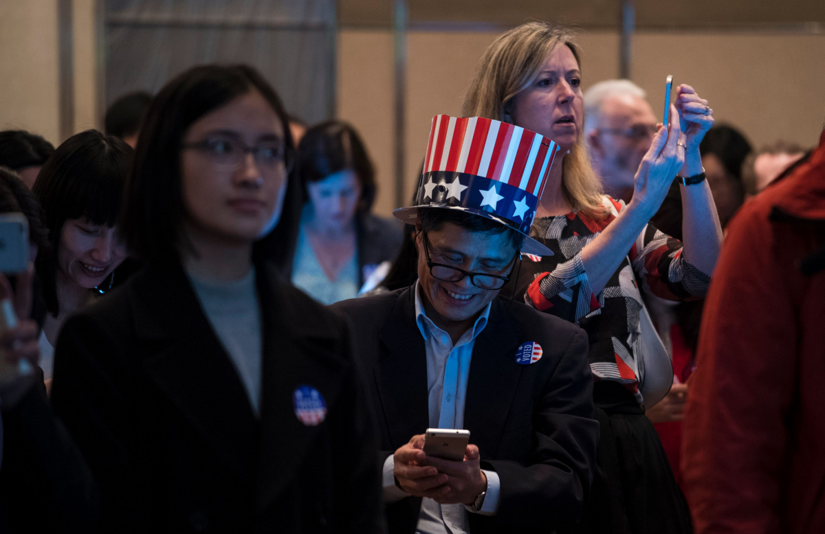 People get news on their smartphones as they follow the results of the final day of the US presidential election at an event organised by the US consulate in Shanghai on November 9, 2016. Donald Trump's stunning performance in the US presidential election