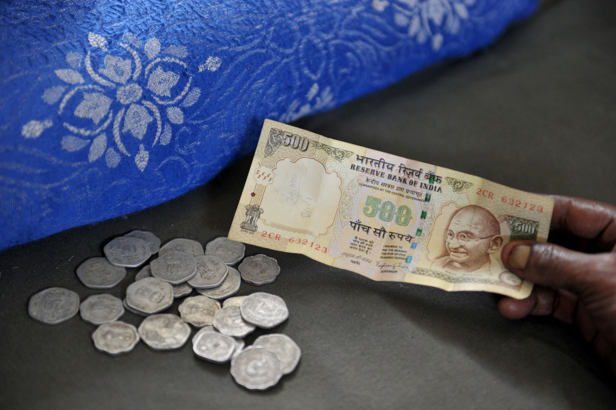 A resident hands a 500 Rupee note to an Indian money lender at his shop in Hyderabad on November 9, 2016, as he seeks to exchange Indian 500 Rupee notes for lesser denominations after the government withdrawal of 500 and 1,000 Indian Rupee notes from fina