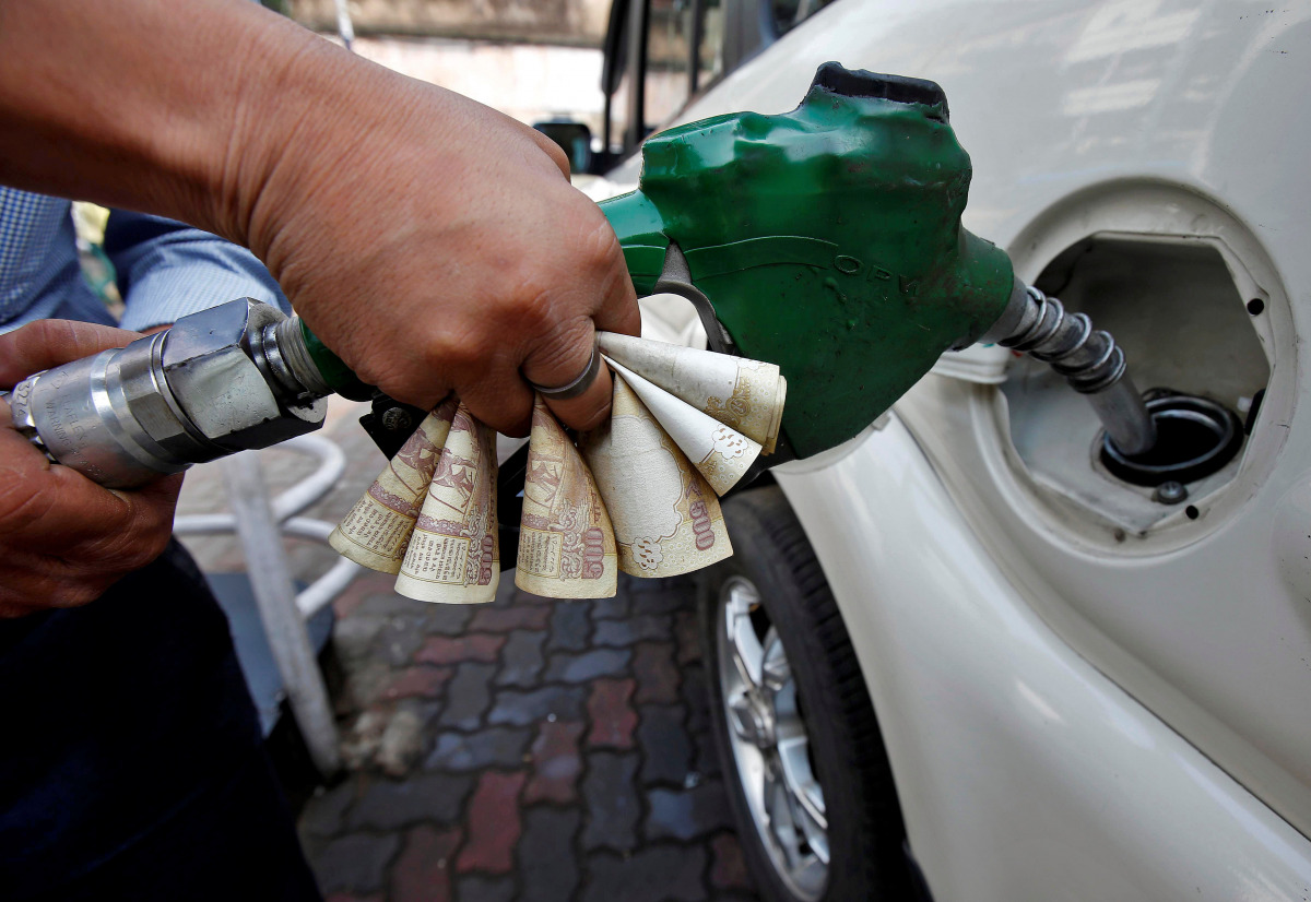 A worker fills diesel in a car as he holds 500 Indian rupee banknotes at a fuel station in Kolkata, India, November 9, 2016. REUTERS/Rupak De Chowdhuri