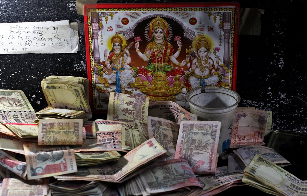 500 and 1000 Indian rupee banknotes are kept in front of an image of the Hindu deities at a cash counter inside a bank in Jammu. Reuters/Mukesh Gupta
