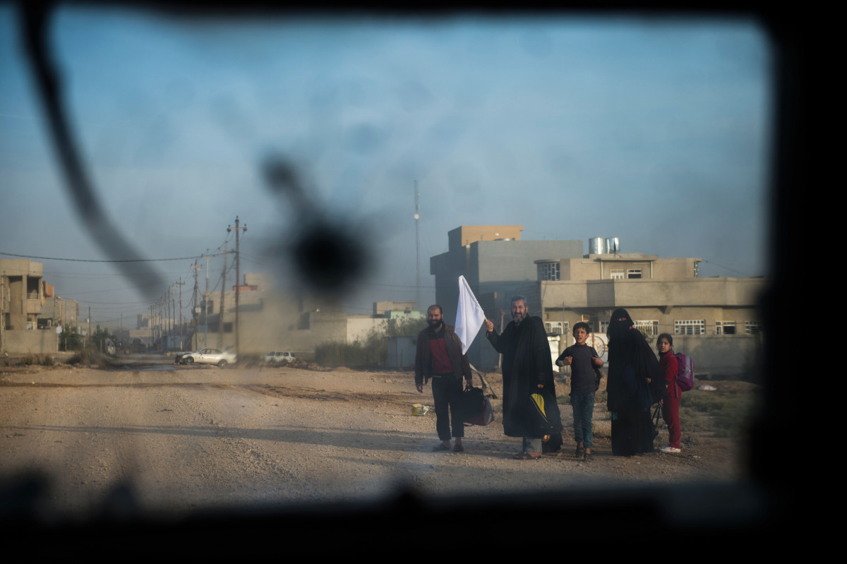 A family holding a white flag looks at a convoy of Iraqi Special Forces' 2nd division driving through the Samah area of Mosul on November 12, 2016. Elite Iraqi forces were engaged in 