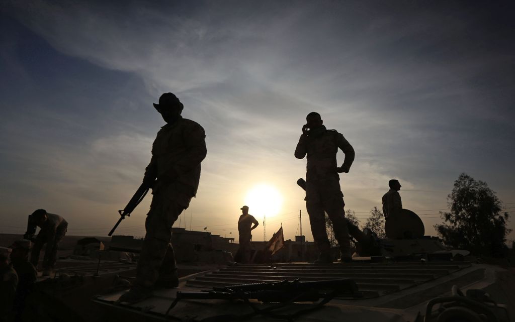 Members of the Iraqi forces stand on their BMP-1 infantry fighting vehicles as they hold a position in the village of Jarif, some 45 kilometres south of Mosul, on November 12, 2016, after retaking it from Islamic State (IS) group jihadists. / AFP / SAFIN 