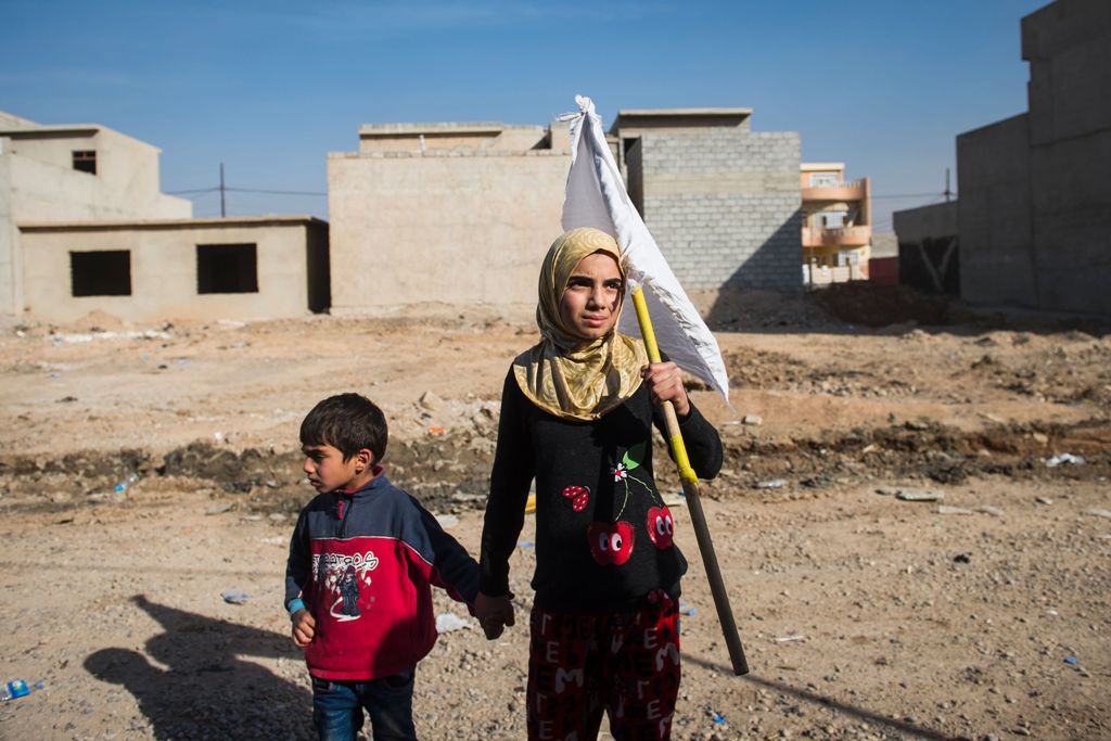 A young girl holding a white flag approaches with her father (unseen) soldiers from the Iraqi Special Forces' 2nd division pushing through the Arbagiah neighbourhood of Mosul as they make their way to their house in the Samah area on November 12, 2016.  A