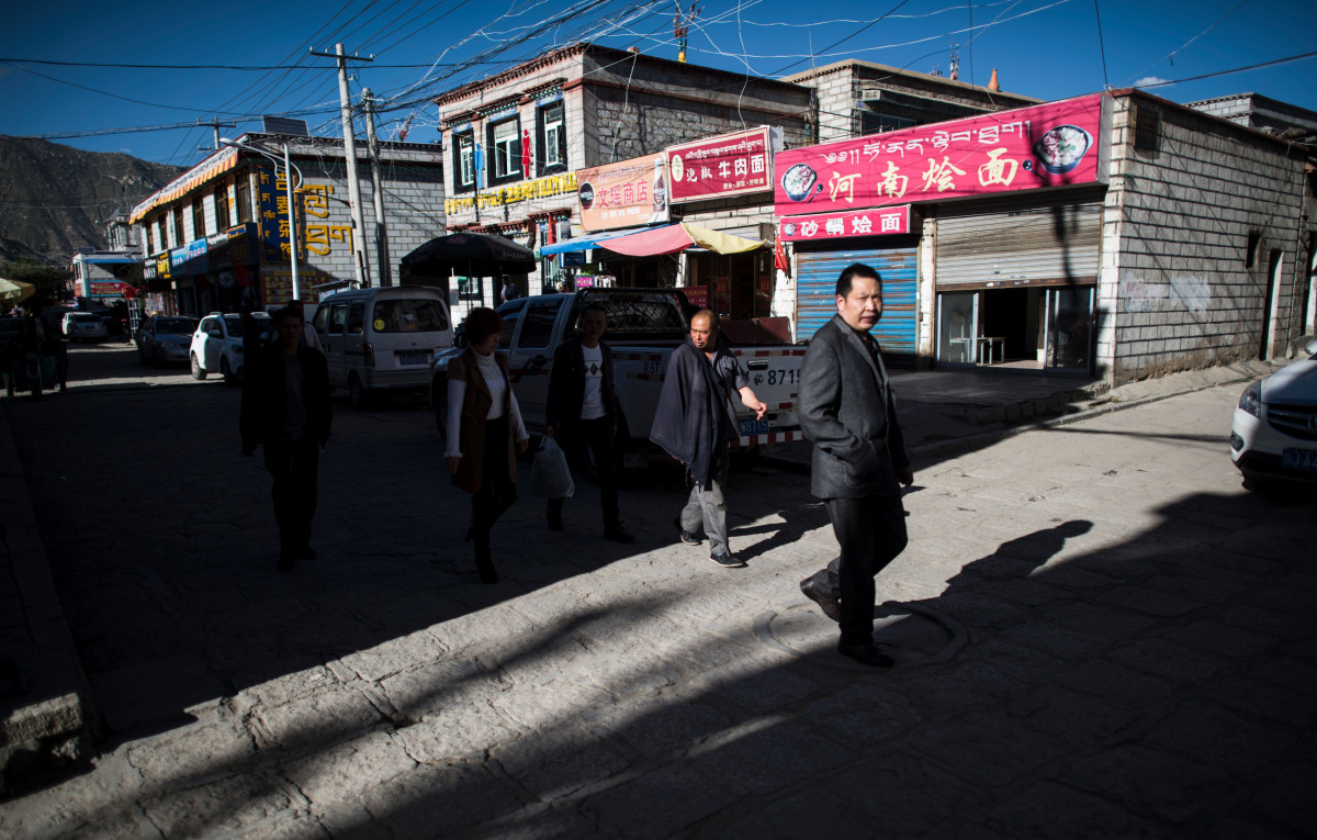 This picture taken on September 10, 2016 shows people walking down a street in Bayi district of the regional capital Lhasa, in China's Tibet Autonomous Region. The traditional teahouses and fashion boutiques of Bayi are the among the liveliest districts o