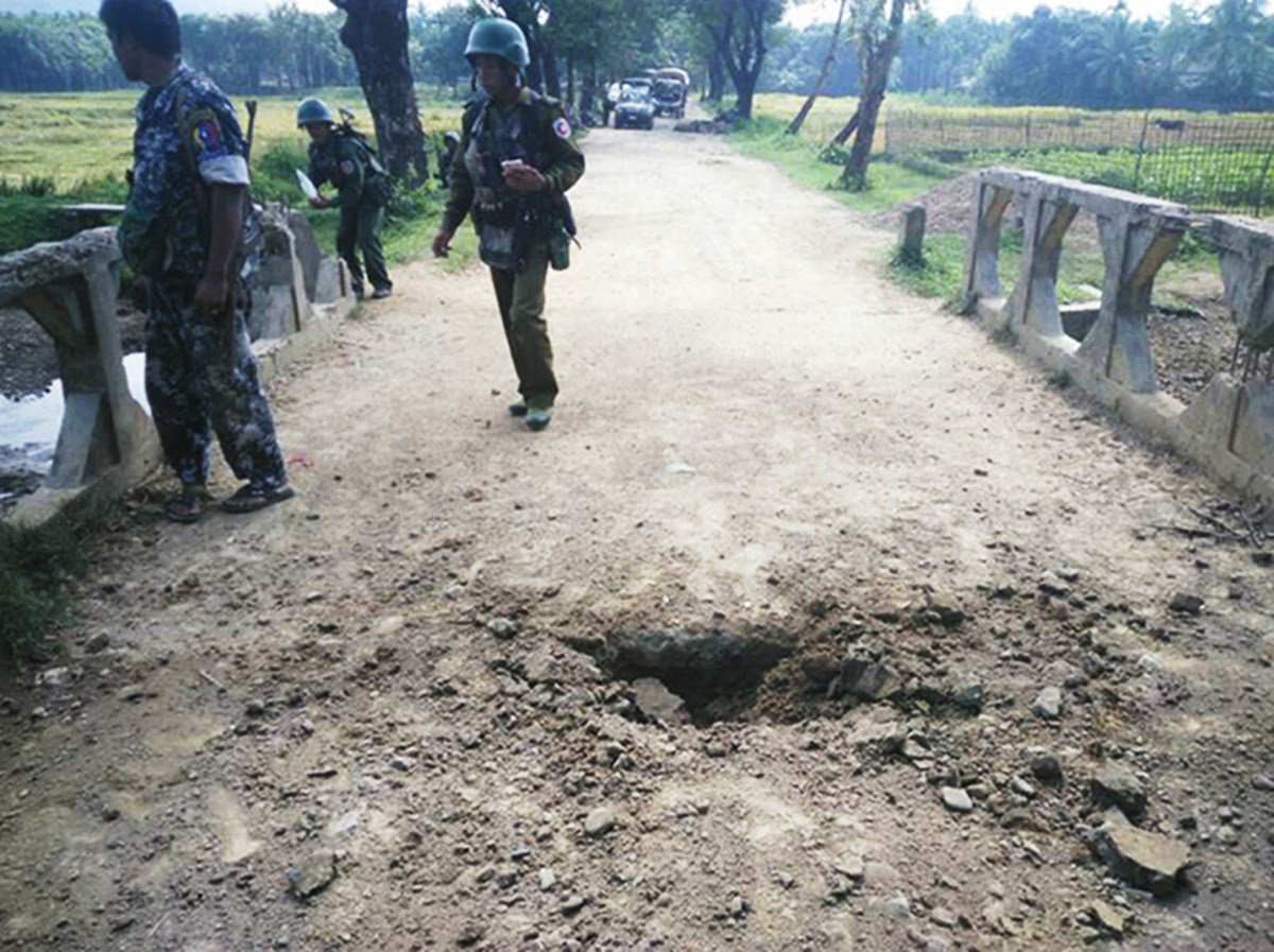 In this handout photograph released by the Myanmar Armed Forces on November 13, 2016, Myanmar soldiers view the crater from a landmine explosion on a bridge in Maung Nama Taung village of Maungdaw, located in Rakhine State near the Bangladesh border on No