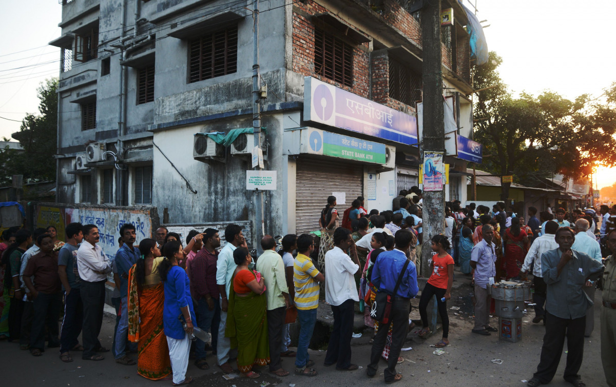 Indian customers queue outside a bank near a shuttered ATM as they wait to try to exchange 500 and 1000 INR notes and deposit money in Siliguri on November 13, 2016. Prime Minister Narendra Modi November 13 made an emotional appeal to people to make India