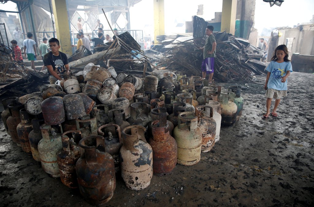 A resident sits near partially burnt LPG cylinders recovered from his family's shop, after a fire in the residential district of Addition Hills in Mandaluyong, Metro Manila, Philippines, November 14, 2016. REUTERS/Erik De Castro